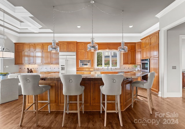 kitchen with light stone countertops, appliances with stainless steel finishes, crown molding, a kitchen island, and hanging light fixtures