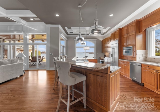 kitchen featuring crown molding, a kitchen island, a healthy amount of sunlight, and appliances with stainless steel finishes