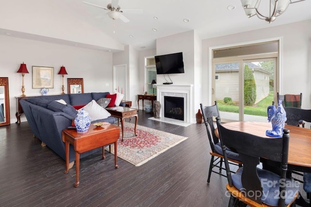 living room featuring lofted ceiling, a premium fireplace, dark hardwood / wood-style flooring, and ceiling fan with notable chandelier