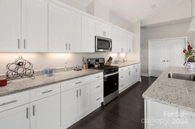 kitchen with light stone countertops, stainless steel appliances, vaulted ceiling, sink, and white cabinetry