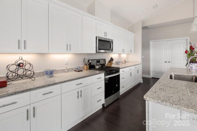 kitchen featuring a sink, dark wood-style floors, stainless steel appliances, white cabinets, and lofted ceiling