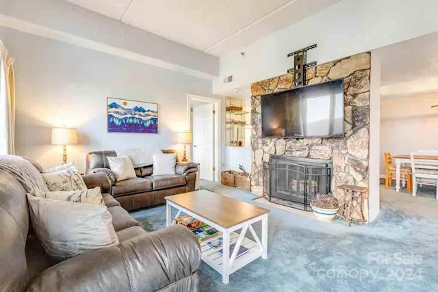 carpeted living room featuring a stone fireplace