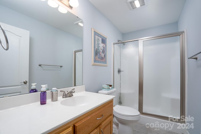 bathroom with a shower with shower door, tile floors, large vanity, and toilet