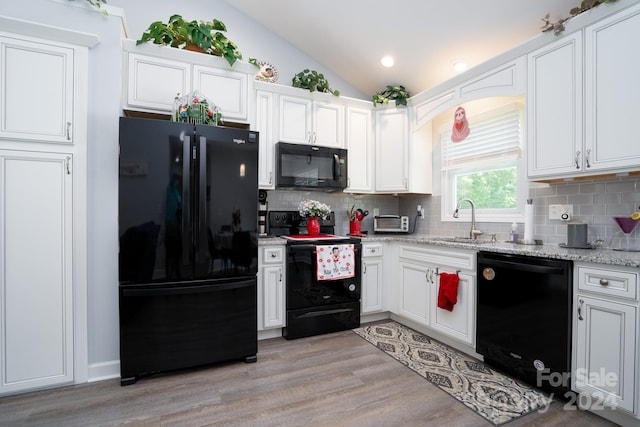 kitchen featuring light hardwood / wood-style flooring, tasteful backsplash, black appliances, sink, and lofted ceiling