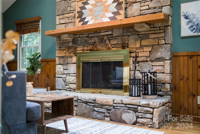 living room with a stone fireplace and wood-type flooring