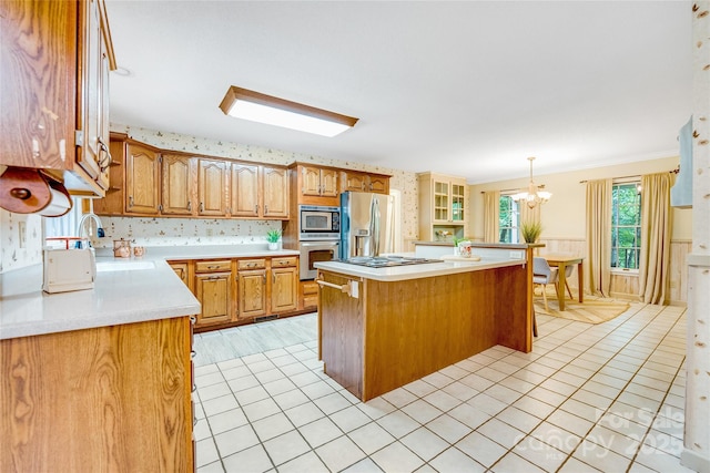 kitchen featuring appliances with stainless steel finishes, a kitchen island, hanging light fixtures, ornamental molding, and a breakfast bar