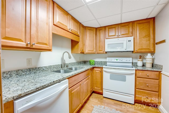 kitchen featuring sink, light stone counters, white appliances, light hardwood / wood-style floors, and a drop ceiling