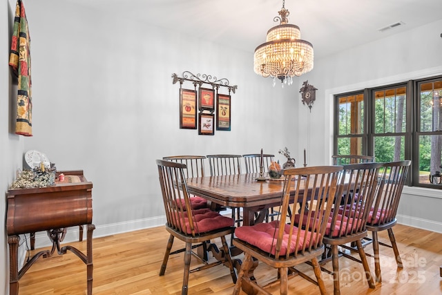 dining room with light hardwood / wood-style flooring and a chandelier