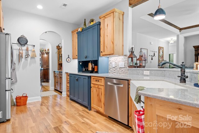 kitchen featuring light stone countertops, light wood-type flooring, stainless steel appliances, pendant lighting, and light brown cabinets