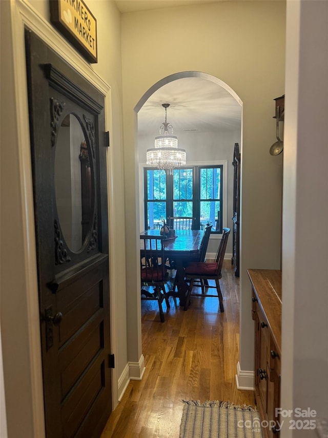 corridor featuring hardwood / wood-style floors and a notable chandelier