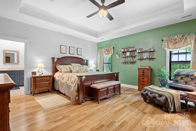 bedroom featuring light hardwood / wood-style flooring, a raised ceiling, ceiling fan, and crown molding