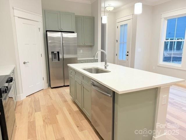 kitchen featuring a kitchen island with sink, light hardwood / wood-style floors, sink, appliances with stainless steel finishes, and pendant lighting