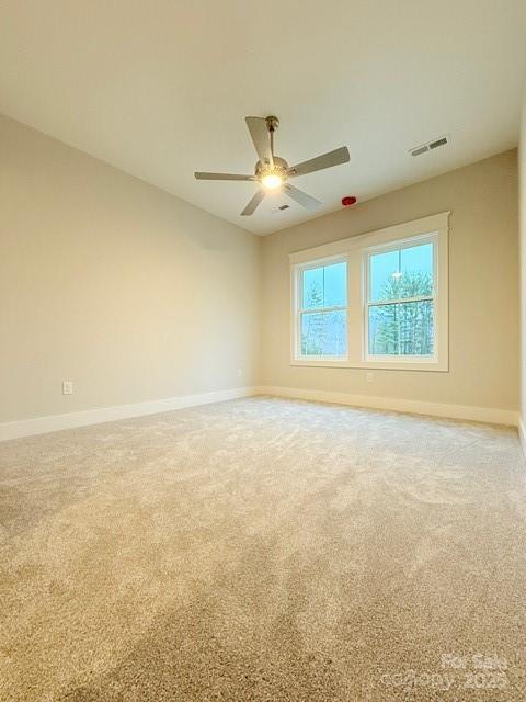 carpeted spare room featuring ceiling fan