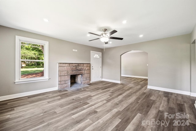 unfurnished living room featuring a stone fireplace, ceiling fan, and light hardwood / wood-style flooring