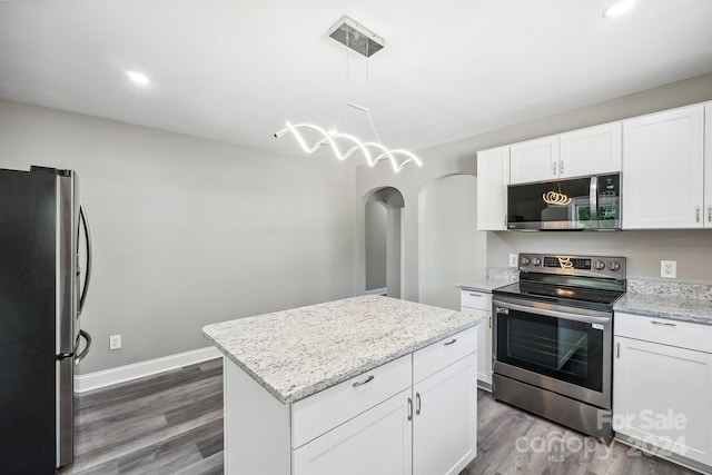 kitchen with white cabinetry, dark wood-type flooring, hanging light fixtures, stainless steel appliances, and a kitchen island