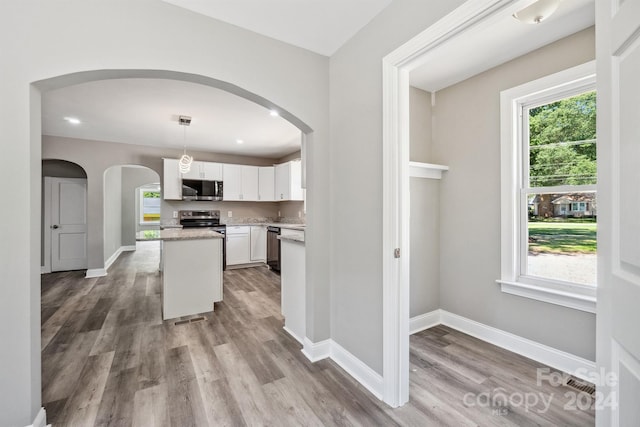 kitchen with white cabinetry, a center island, dishwasher, light hardwood / wood-style floors, and decorative light fixtures