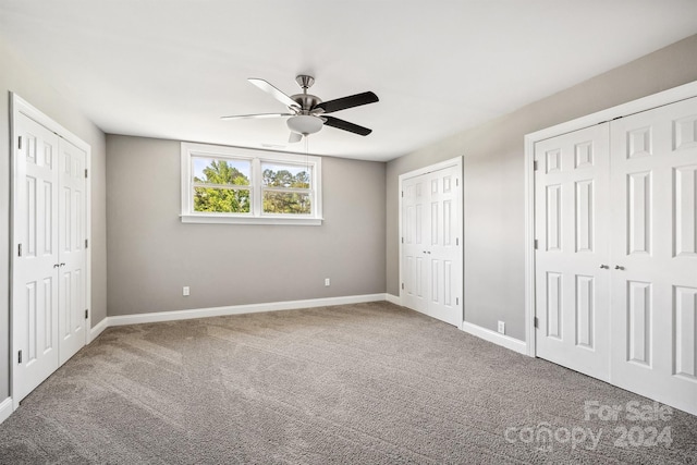 unfurnished bedroom with ceiling fan, carpet floors, and two closets