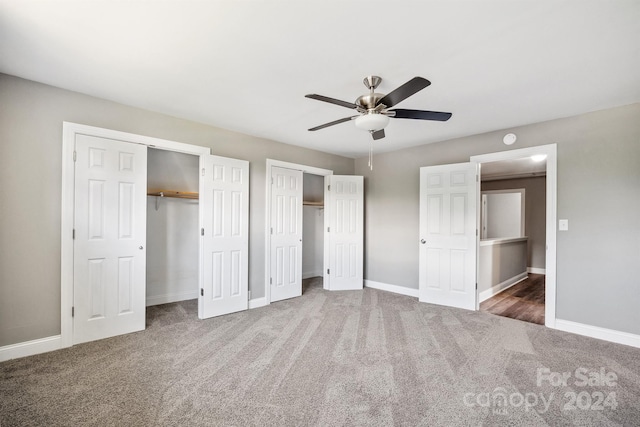 unfurnished bedroom with ceiling fan, carpet, and two closets