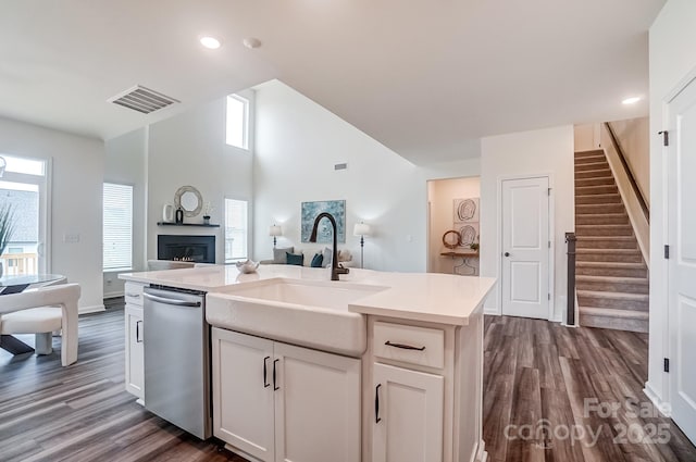 kitchen with dark wood-type flooring, sink, white cabinetry, dishwasher, and a kitchen island with sink