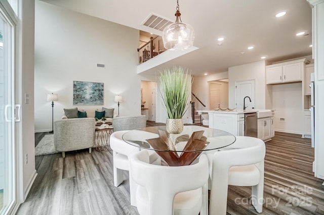 dining space featuring wood-type flooring, sink, and a notable chandelier