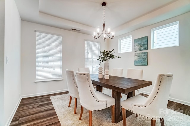 dining area featuring a notable chandelier, dark hardwood / wood-style flooring, and a tray ceiling