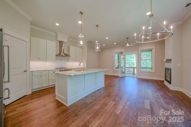 167 Collin Pl Unit 21, Asheville, NC 28804 - kitchen featuring wood finished floors, ornamental molding, wall chimney exhaust hood, white cabinetry, and a glass covered fireplace