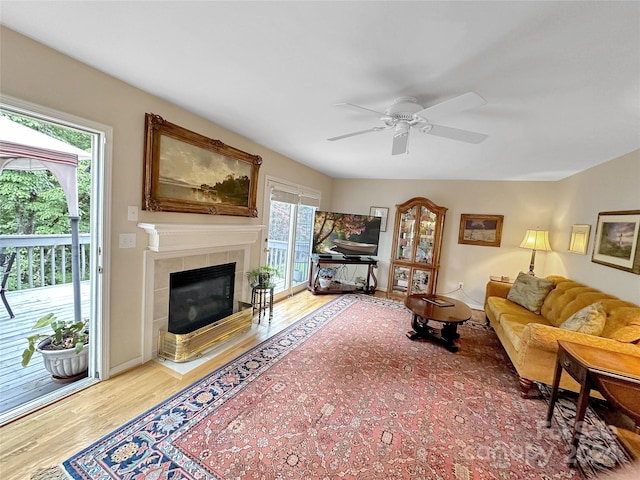 living room featuring ceiling fan, wood-type flooring, a fireplace, and plenty of natural light