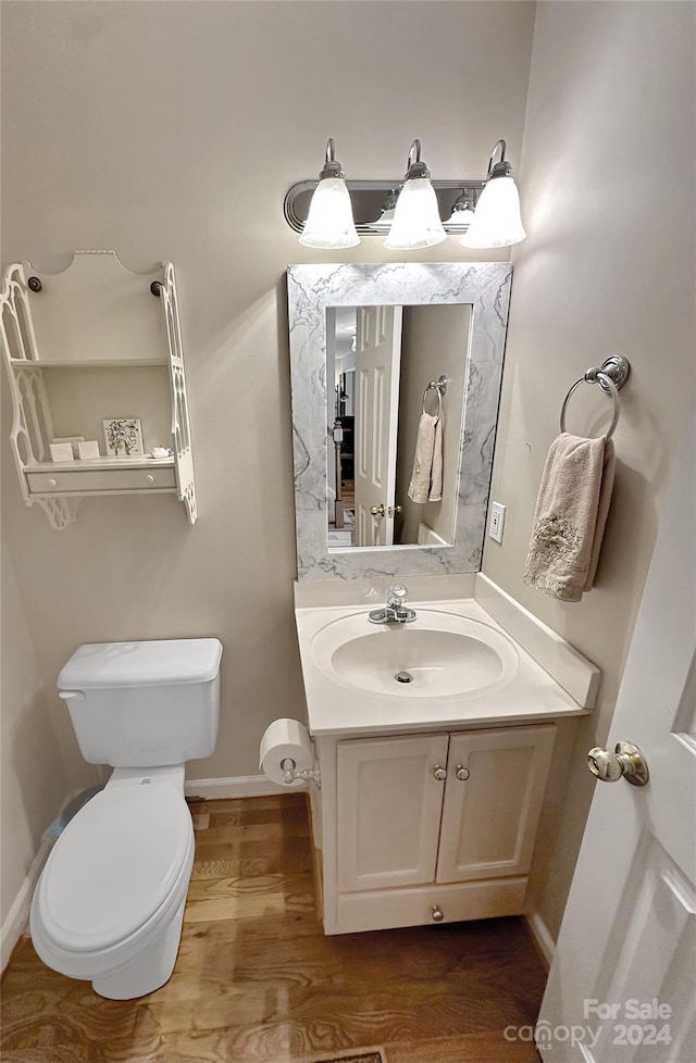 bathroom with hardwood / wood-style flooring, toilet, and vanity