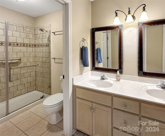 bathroom with a shower with shower door, tile patterned floors, vanity, and toilet