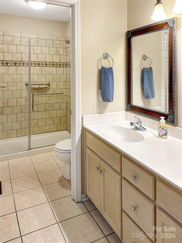 bathroom with toilet, vanity, tile patterned flooring, and walk in shower