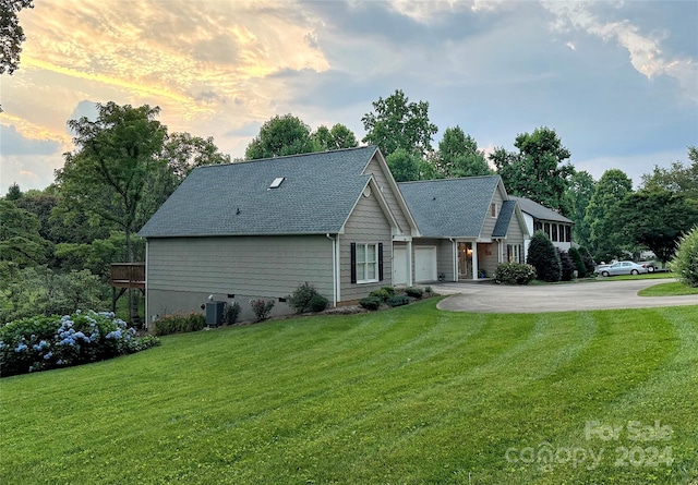 exterior space with a garage, a yard, and central AC