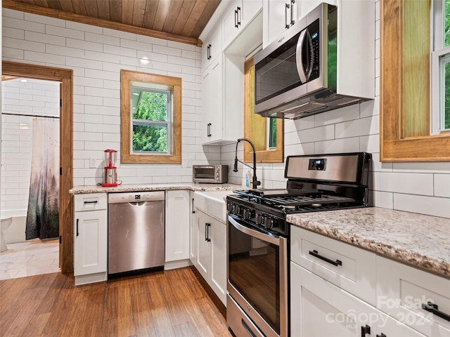 kitchen featuring light stone countertops, white cabinets, appliances with stainless steel finishes, and wood ceiling