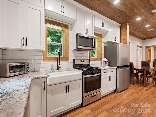 kitchen with white cabinets, stainless steel appliances, tasteful backsplash, sink, and wooden ceiling