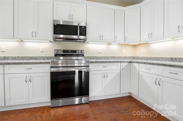 kitchen with white cabinets, light stone counters, dark wood-type flooring, and appliances with stainless steel finishes