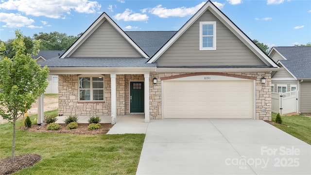 view of front of property featuring concrete driveway, an attached garage, a front lawn, and roof with shingles