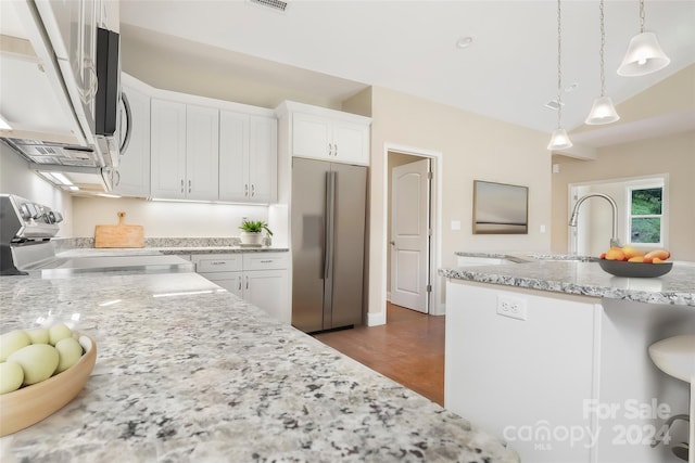 kitchen with stainless steel fridge, stove, white cabinetry, and pendant lighting