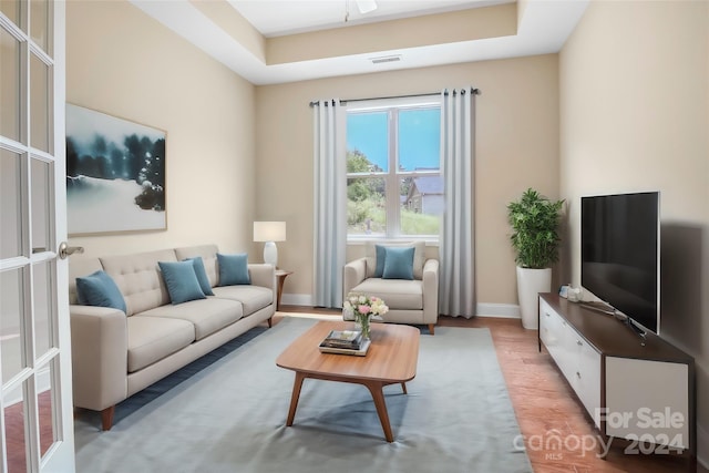 living room featuring a tray ceiling and light hardwood / wood-style floors