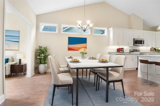 dining space with baseboards, a notable chandelier, light wood-style flooring, and high vaulted ceiling