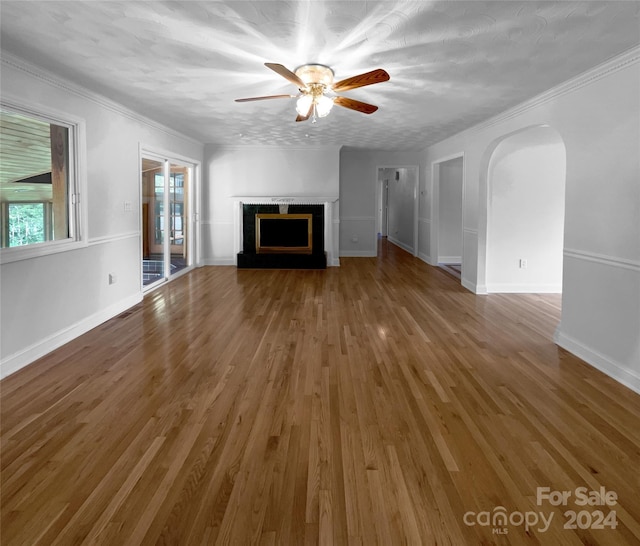 unfurnished living room with ceiling fan, wood-type flooring, a textured ceiling, and ornamental molding