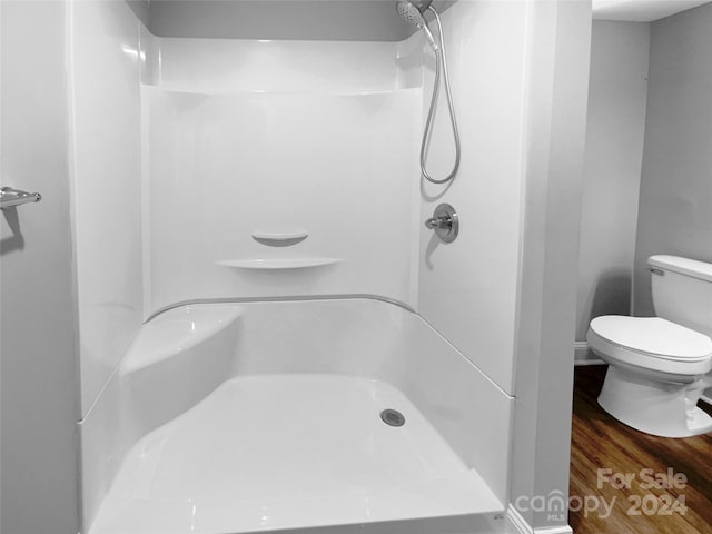 bathroom with a shower, hardwood / wood-style flooring, and toilet