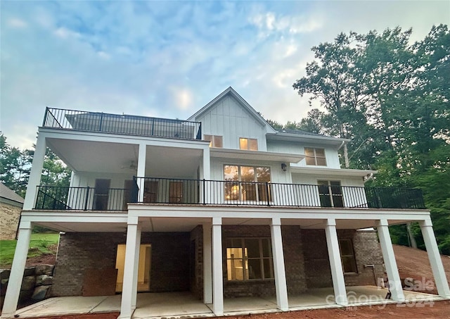 rear view of house featuring a balcony, board and batten siding, and a patio