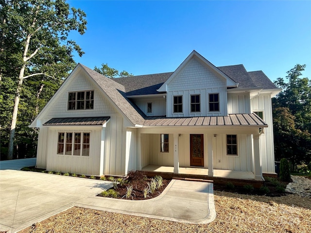 modern farmhouse style home featuring metal roof, a porch, a shingled roof, board and batten siding, and a standing seam roof