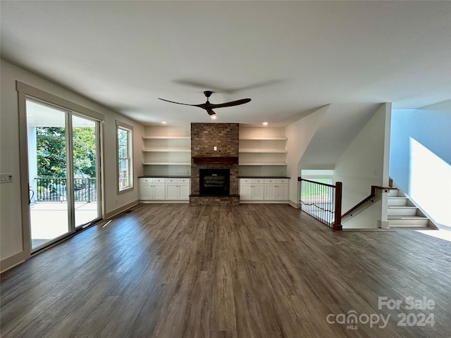 unfurnished living room with a brick fireplace, dark wood-style flooring, ceiling fan, and baseboards