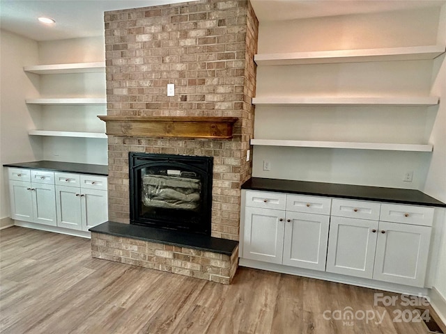 unfurnished living room featuring a brick fireplace and light wood-style flooring