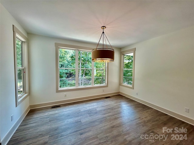 unfurnished dining area with baseboards, dark wood finished floors, visible vents, and a healthy amount of sunlight