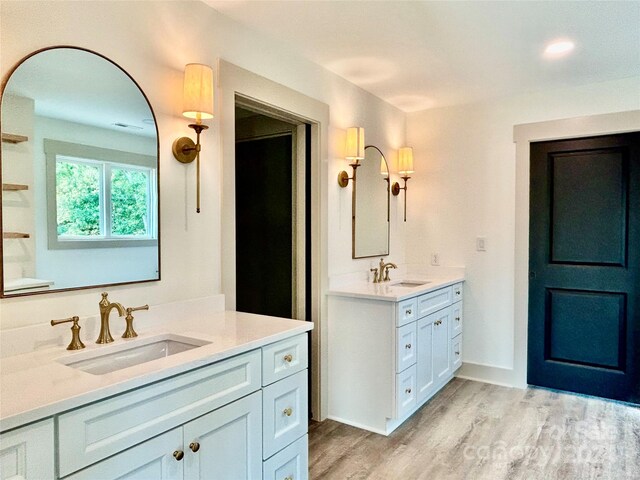 bathroom with two vanities, a sink, baseboards, and wood finished floors