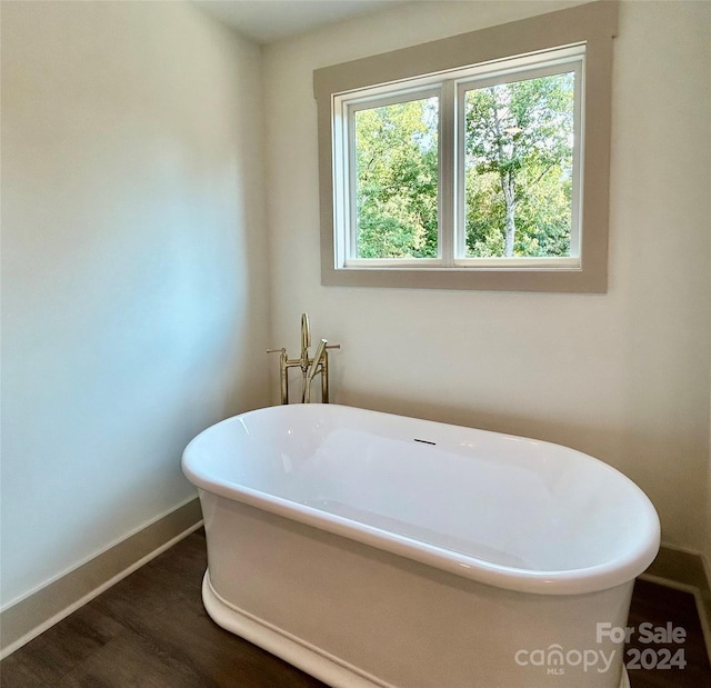 bathroom with a freestanding tub, baseboards, and wood finished floors