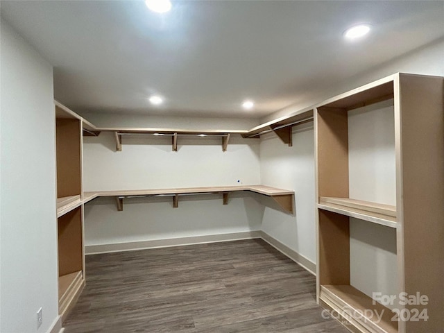 spacious closet with dark wood-style floors and built in desk