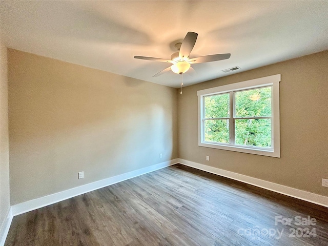 spare room featuring a ceiling fan, baseboards, visible vents, and dark wood-type flooring