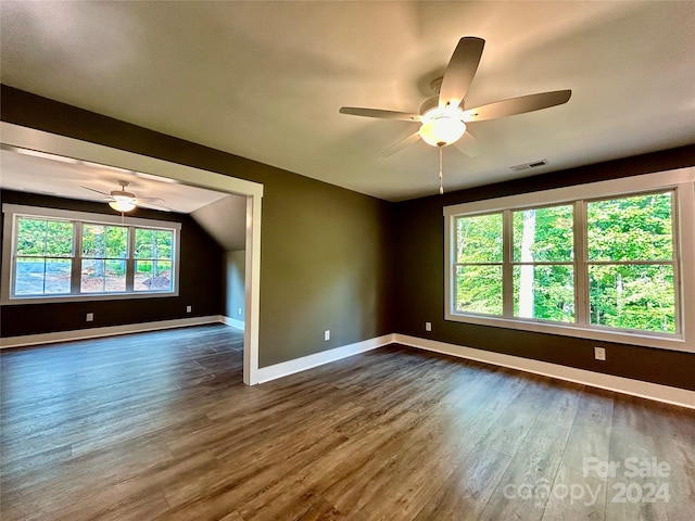 unfurnished room with lofted ceiling, a ceiling fan, visible vents, baseboards, and dark wood finished floors